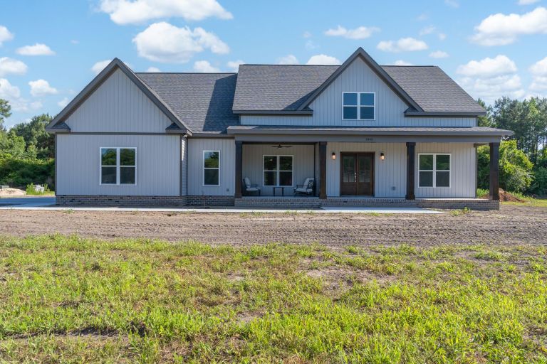 The Bruce Build: White custom home with board and batten siding and a large covered front porch on Hwy 111 in Eastern NC by Signature Homes.