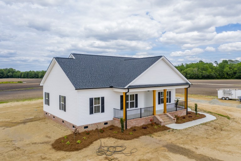 The Andrews Build: White custom home with black shutters and wood-wrapped porch pillars on Stroud Road in Deep Run, NC.