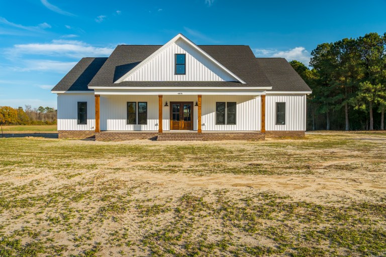 The Williams Build: White modern farmhouse with natural wood porch pillars on Hwy 11 in Deep Run, NC by Signature Homes.