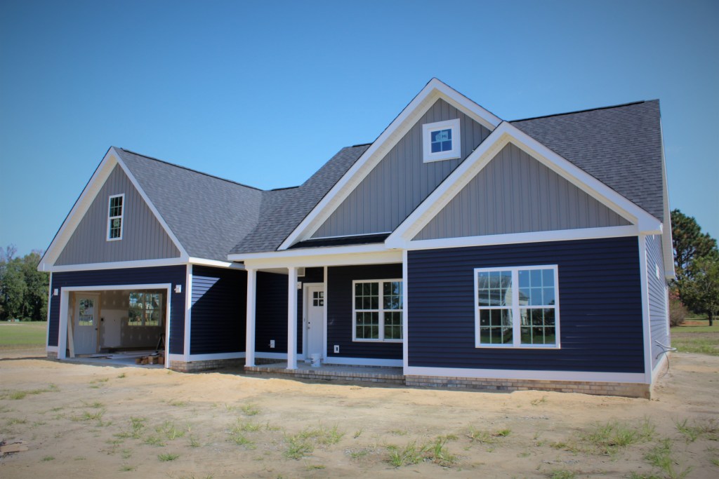 The Murphy Build: Navy blue craftsman-style custom home with white trim and front porch by Signature Homes ENC.